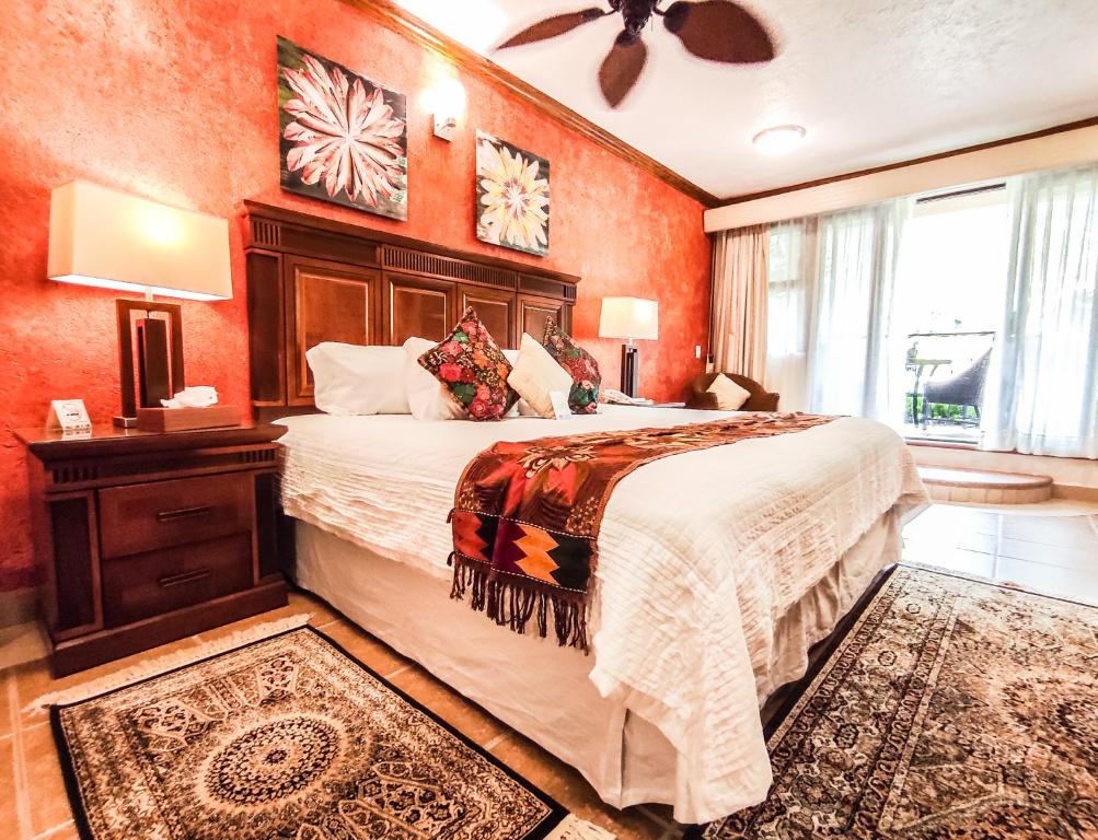 1 dormitorio con 1 cama grande y paredes de color naranja en La Buena Vibra Retreat and Spa Hotel Adults Only en Tepoztlán