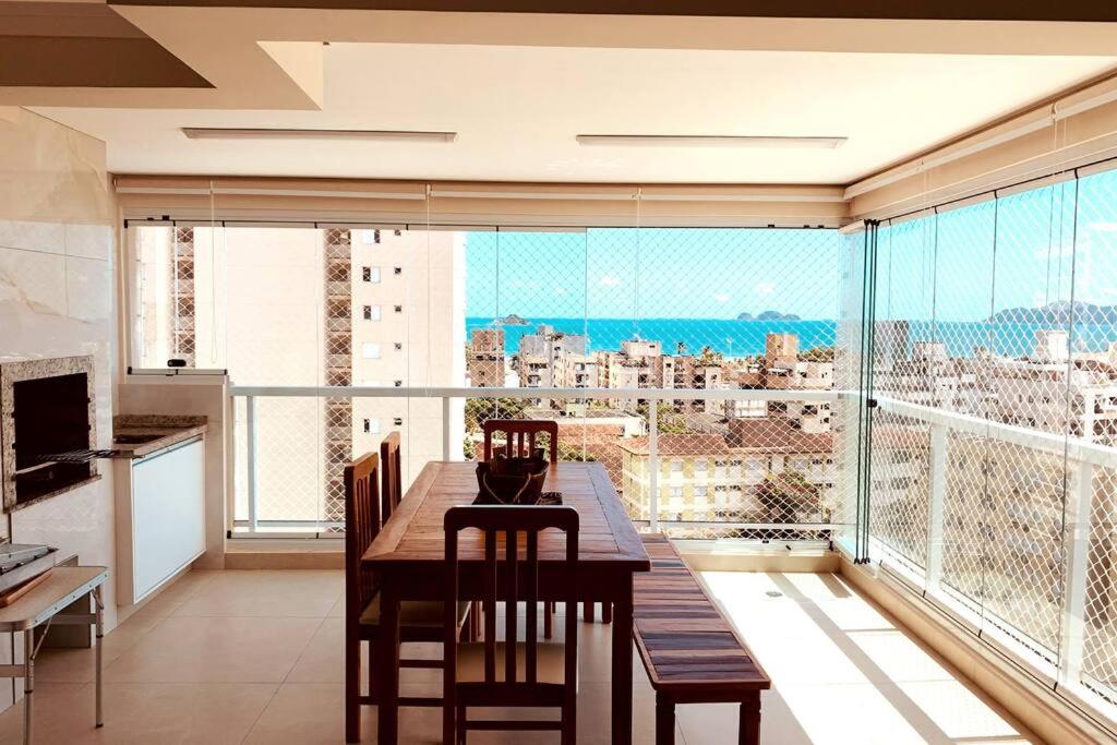 a dining room with a table and a large window at Condominio Club, Vista para o mar, Churrasqueira in Guarujá
