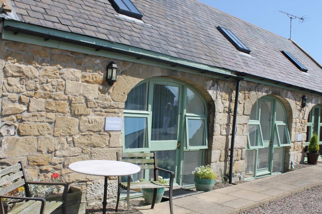 a stone building with a table and chairs in front of it at Bucklaw Cottage in Alnwick