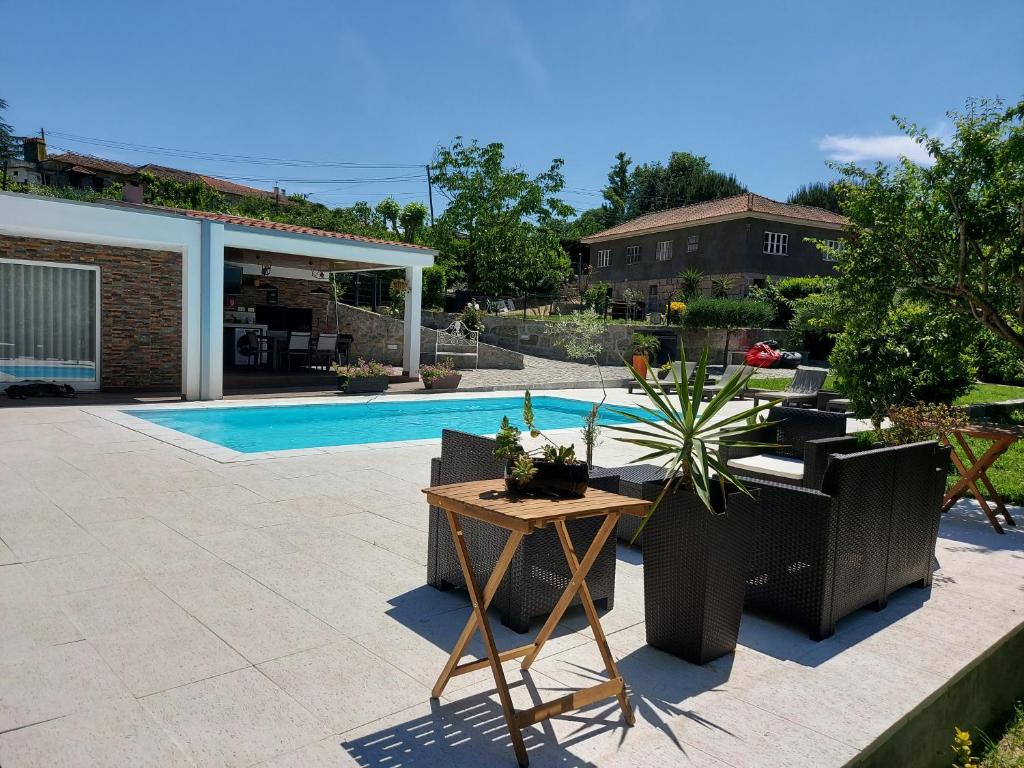 um pátio com uma mesa e cadeiras e uma piscina em Villa Casa de Santo Antonio em Marco de Canavezes