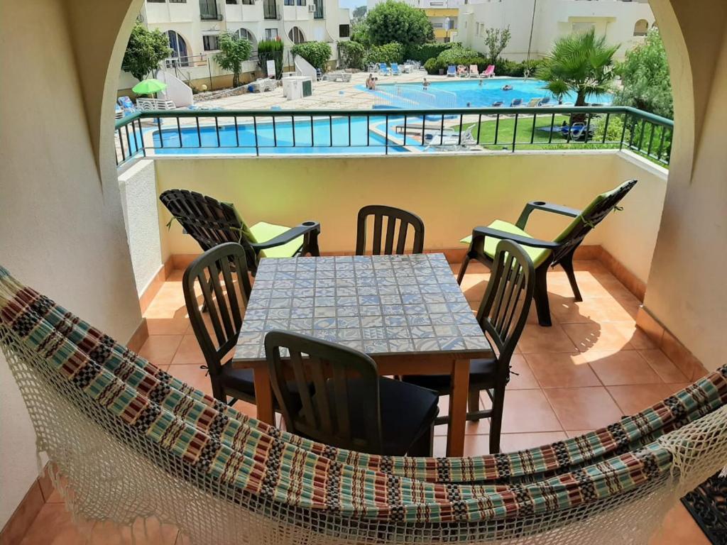 un patio con tavolo, sedie e piscina di T1 Poente da Aldeia 336 Albufeira ad Albufeira