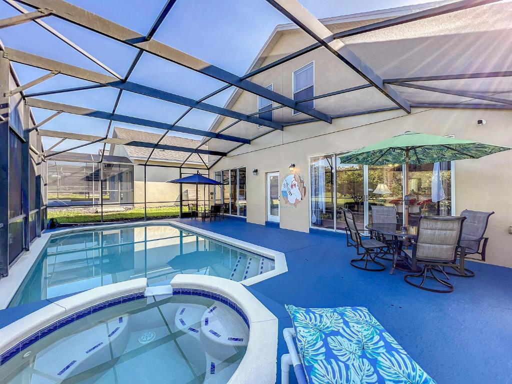 einen Pool mit einem Tisch, Stühlen und einem Sonnenschirm in der Unterkunft Scuttle Vacation Pool Home Wspa in Orlando
