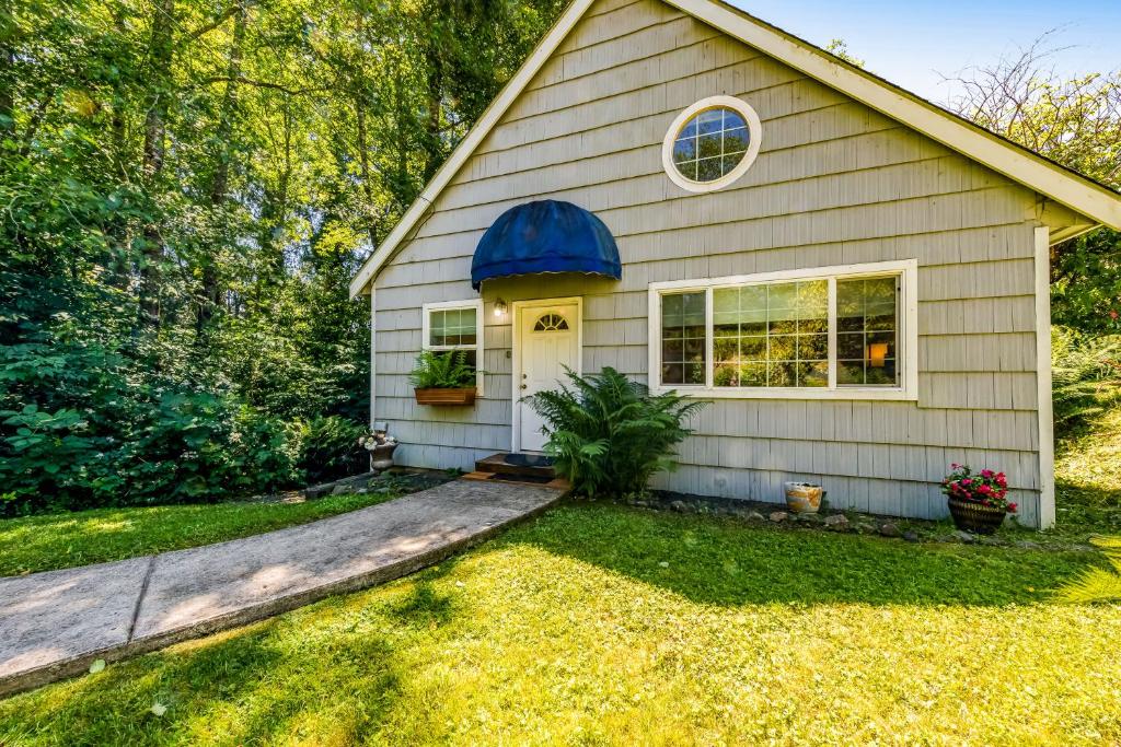 uma pequena casa com uma porta azul e um quintal em Alder Cove em Tillamook