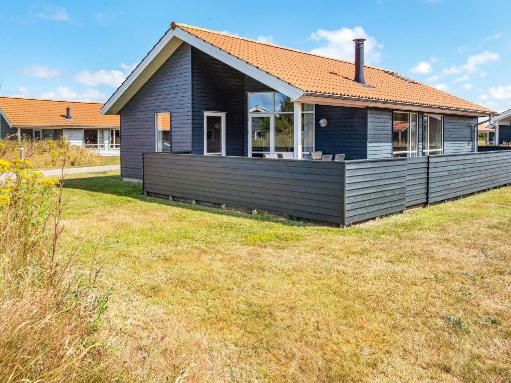 uma casa preta com um grande relvado em frente em Holiday home Ulfborg XXII em Ulfborg