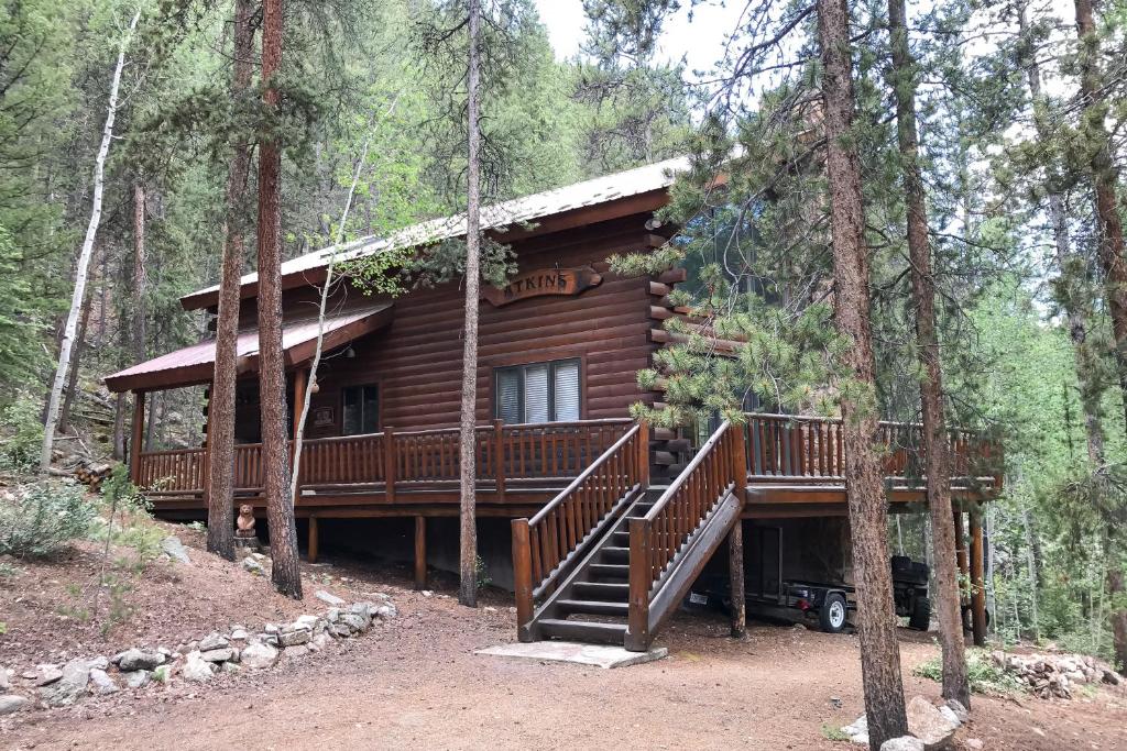 una baita di tronchi nel bosco con un ampio ponte di Atkins Cabin a Almont