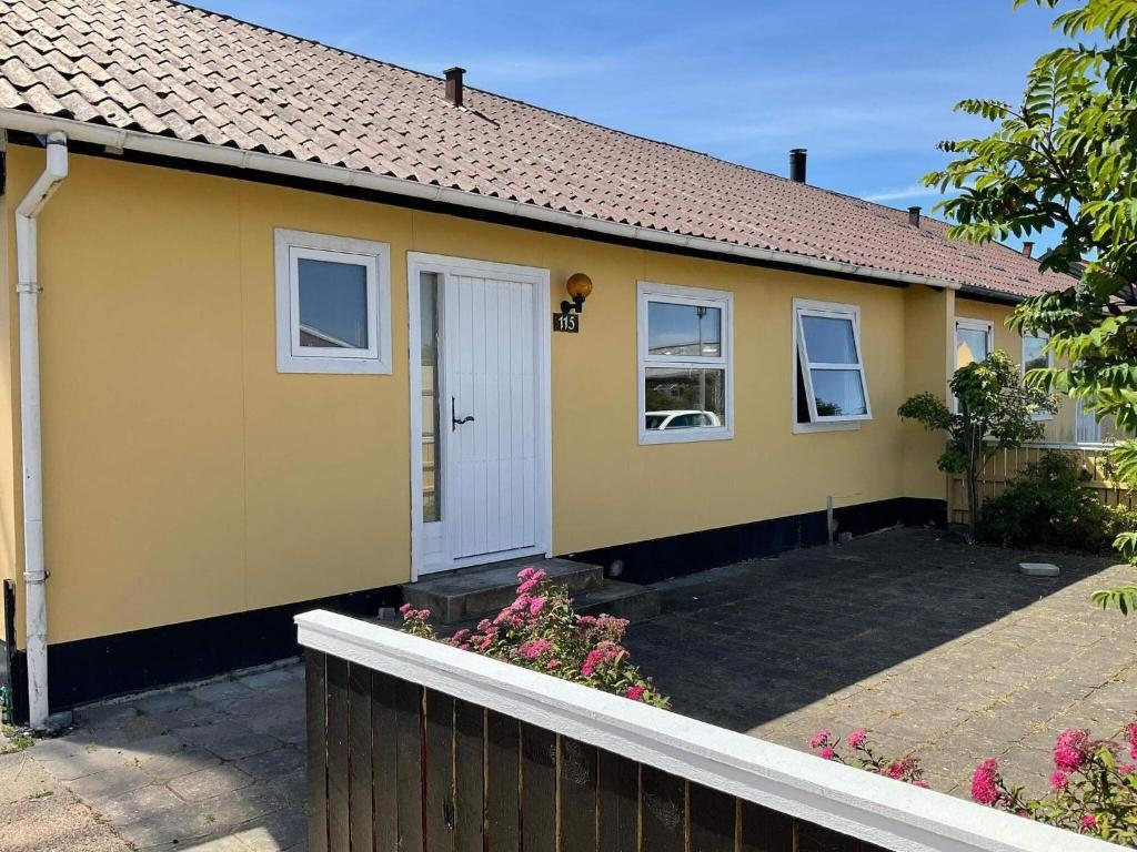 uma casa amarela com uma porta branca e uma cerca em Holiday home Skagen LXVI em Skagen
