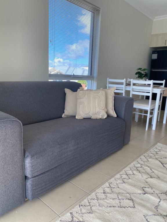a blue couch with two pillows on it in a living room at Modern Luxury 1 Bedroom Apartment - Walk to the shops! Free Wifi in Clarkson