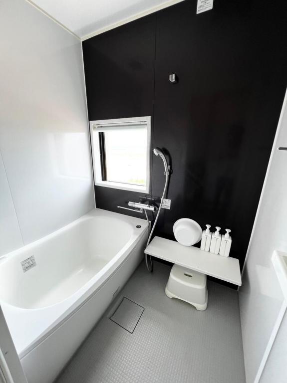 a white bathroom with a tub and a toilet at ゴールデンマイルヴィラ in Amami