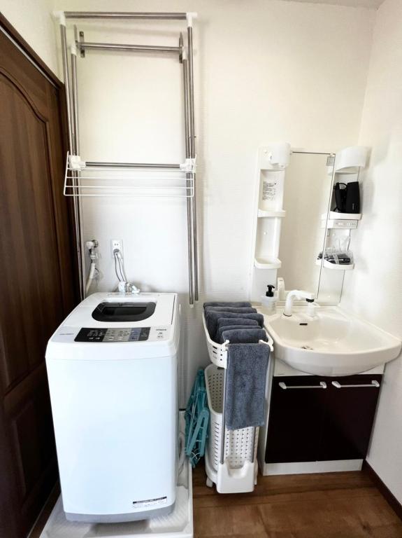 a small bathroom with a sink and a white refrigerator at ゴールデンマイルヴィラ in Amami
