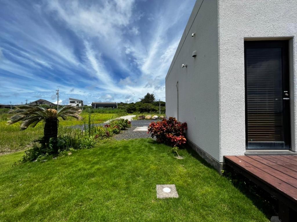 a house with a grass yard next to a building at ゴールデンマイルヴィラ in Amami