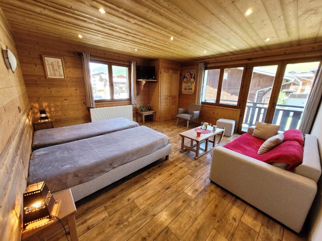 une grande chambre avec deux lits et un canapé dans l'établissement Louez un appartement 3 étoiles à deux pas des remontées mécaniques au cœur des Gets ! - FR-1-598-102, aux Gets