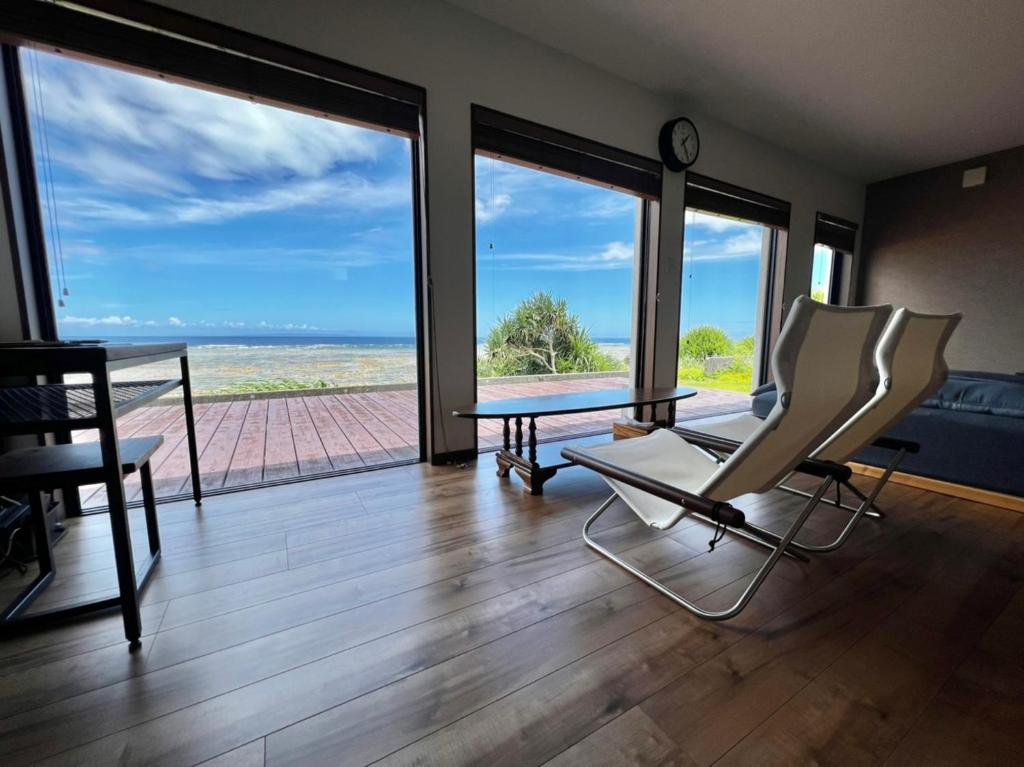 a living room with a table and chairs and a view of the ocean at ゴールデンマイルヴィラ in Amami