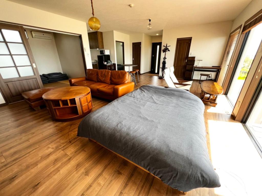 a living room with a bed and a couch at ゴールデンマイルヴィラ in Amami