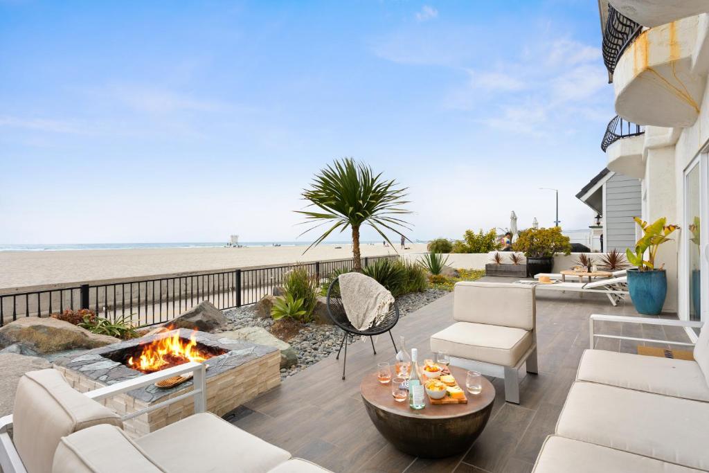 een patio met een vuurplaats naast het strand bij Shoreline by AvantStay Spectacular Beachfront Home w Fire Pit Spa Pool Table in San Diego