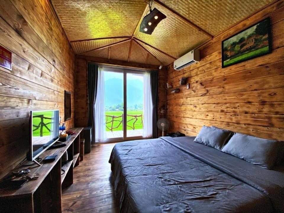 a bedroom with a large bed and a large window at Mai Chau Countryside Homestay in Mai Chau