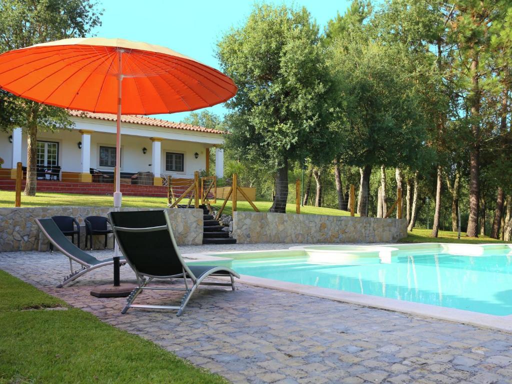 una sombrilla y sillas junto a la piscina en Luxurious Villa in Caldas da Rainha with Swimming Pool en Salir de Matos