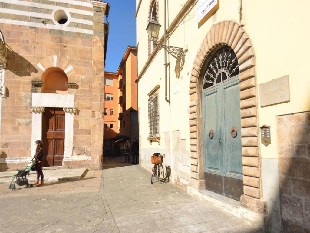 a woman walking a bike next to a building with a blue door at Apartment in Lucca near Piazza Napoleone in Lucca