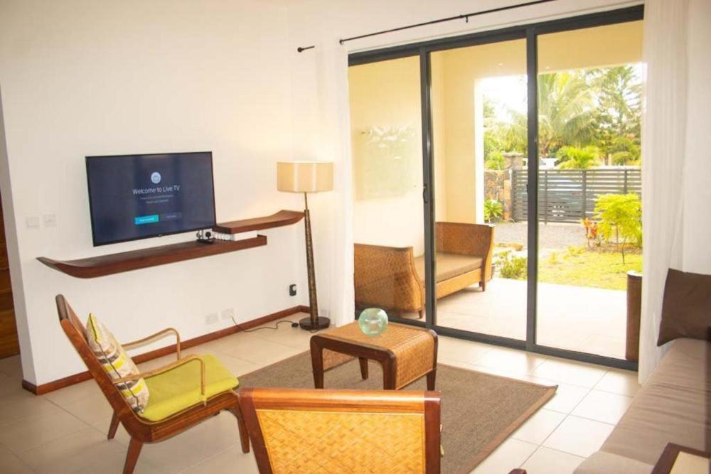 a living room with a tv and a couch and chairs at Les Villas Thorel in Rivière Noire