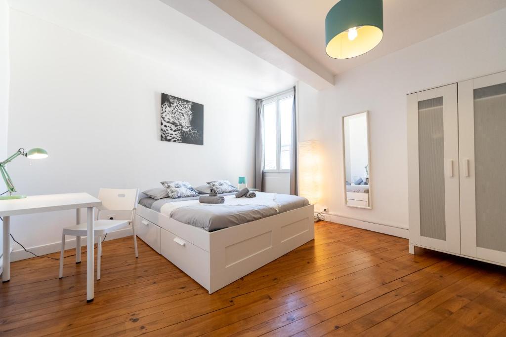 a white bedroom with a bed and a desk at KASA ZAMBEZE - Spacieux - WIFI in Saint-Étienne