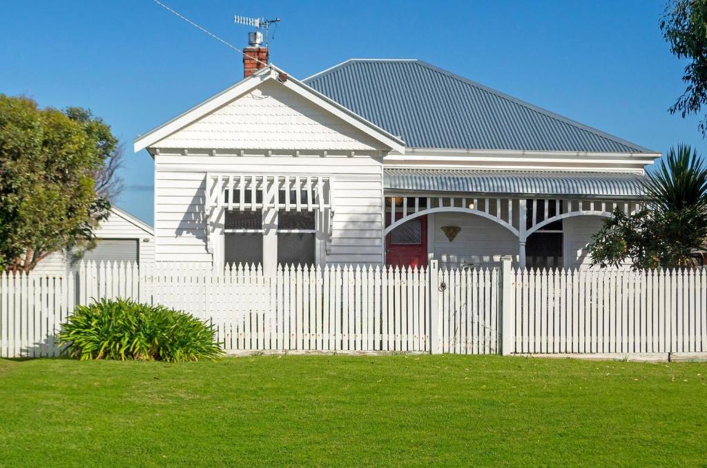 a white house with a white picket fence at Avery Cottage in Port Fairy