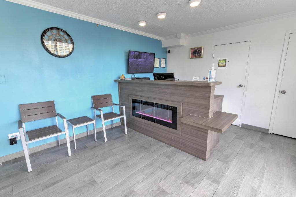 a living room with a fireplace and two chairs at White Marlin Inn - Virginia Beach in Virginia Beach