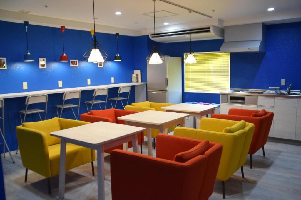 a restaurant with tables and chairs and blue walls at Hostel Anchorage in Kobe