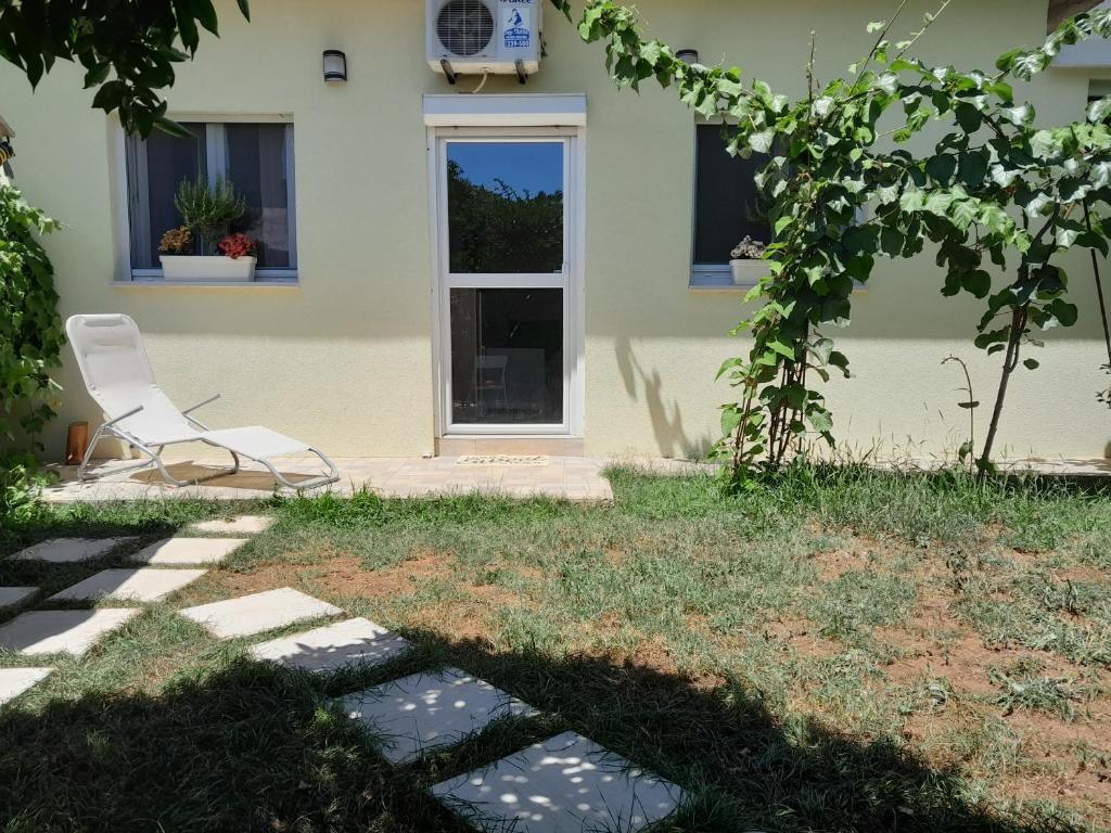 una sedia bianca seduta di fronte a una casa di MAJA GARDEN a Zara (Zadar)