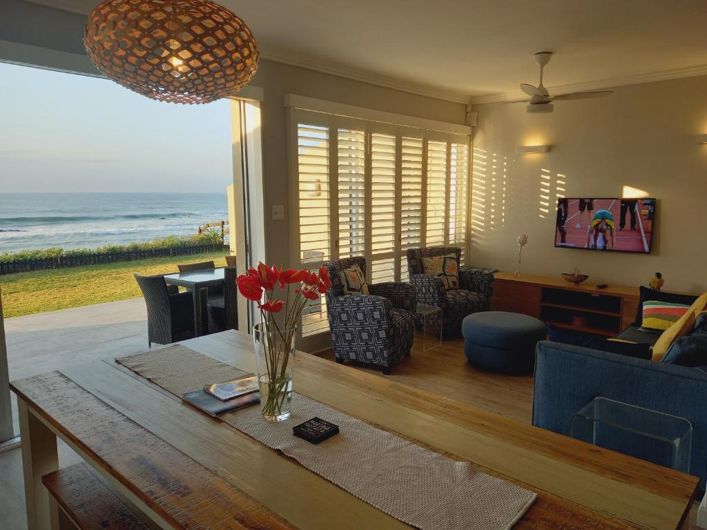 Modern & Luxurious Beachfront Villa في باليتو: غرفة معيشة مع طاولة وإطلالة على المحيط