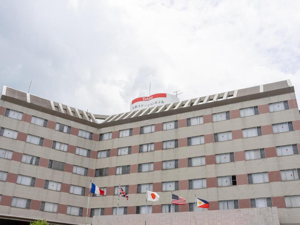 a building with flags on the top of it at Tabist Yabuki Station Hotel in Yabuki