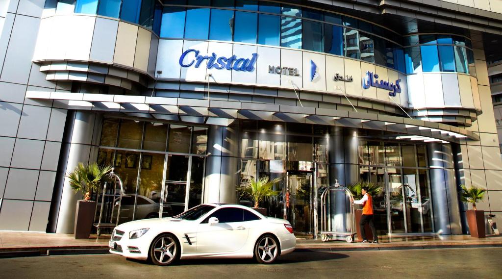 a white car parked in front of a building at Cristal Hotel Abu Dhabi in Abu Dhabi