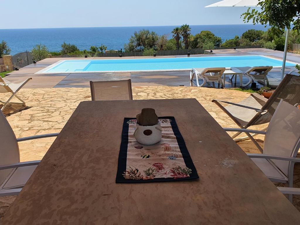 kapelusz siedzący na drewnianym stole obok basenu w obiekcie Villa Pozzo Pasulo w mieście Torre Vado