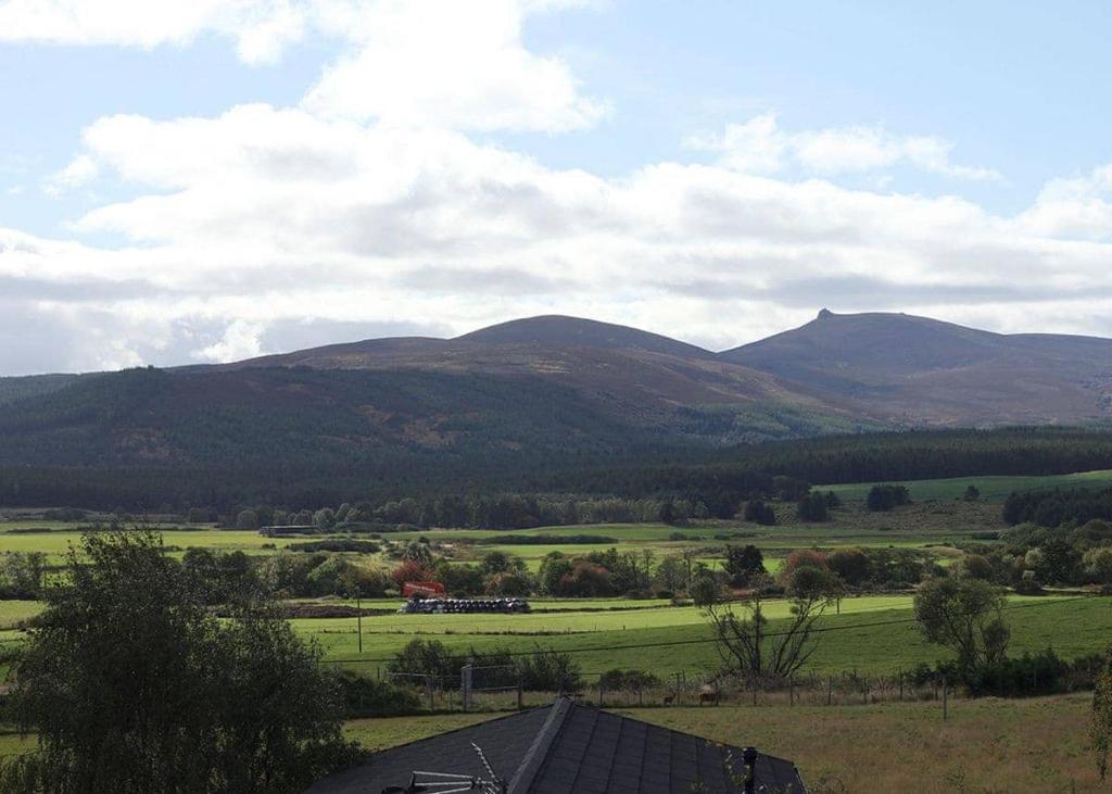 a view of a field with mountains in the background at Castlewood Lodges in Strachan