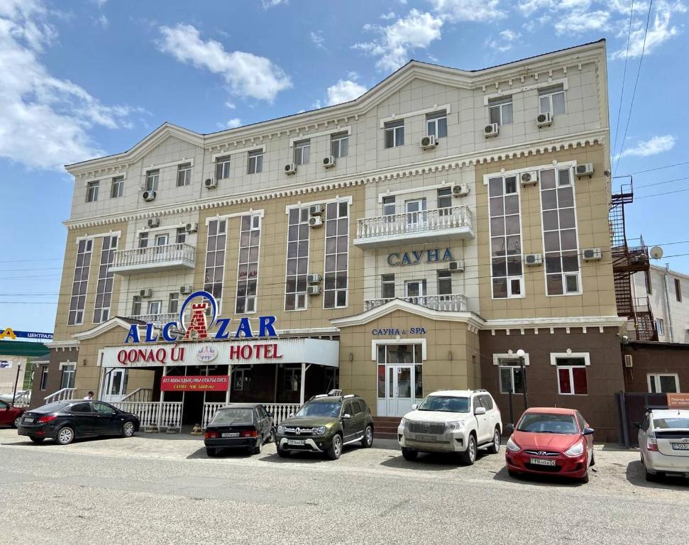 un gran edificio con coches estacionados frente a él en ALCAZAR, en Atyraū