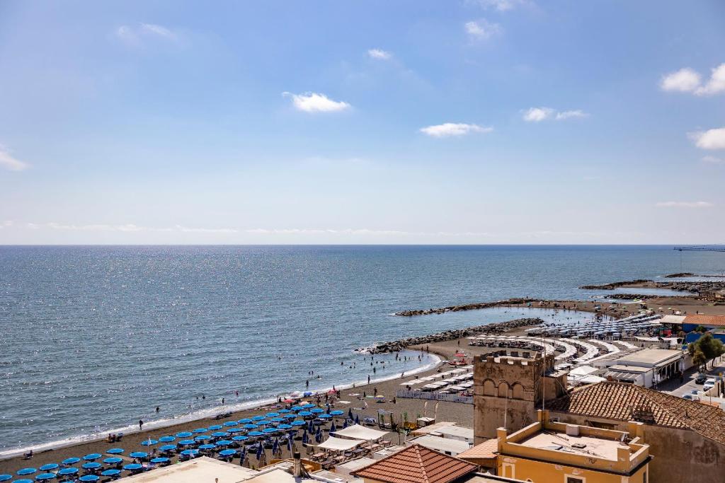 una playa con sombrillas azules y blancas y el océano en Hotel Villa Margherita, en Ladispoli