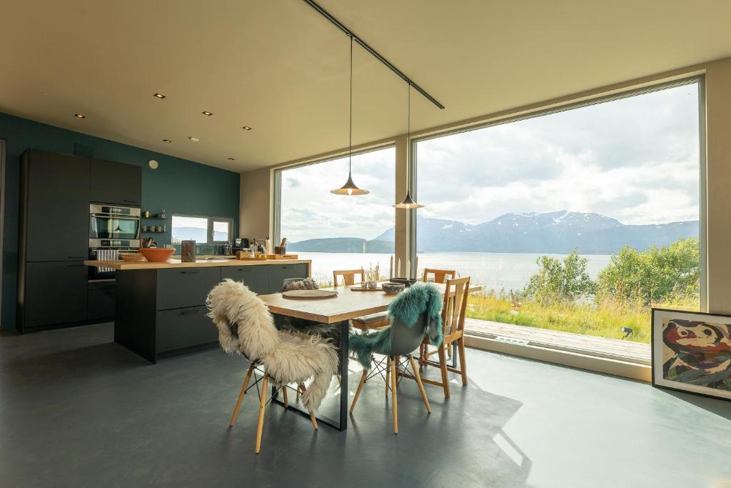 Indulge in beautiful nature and amazing views. في Mortenhals: مطبخ مع طاولة وكراسي ونافذة كبيرة