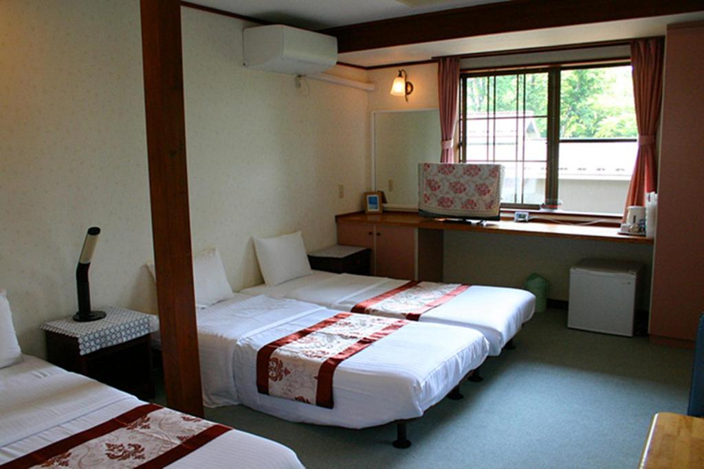une chambre d'hôtel avec deux lits et une fenêtre dans l'établissement Pension Marieペンションマリエ, à Yamanakako 37 autres photos
