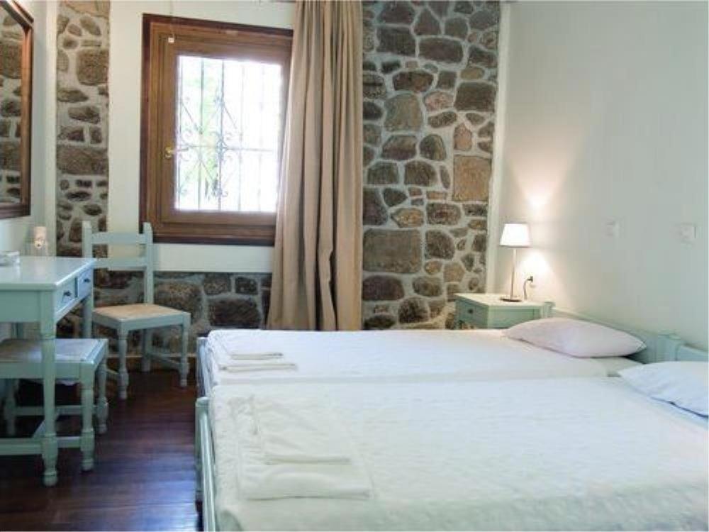 een slaapkamer met 2 bedden, een wastafel en een raam bij Olive Press Hotel & Apartments in Mithimna