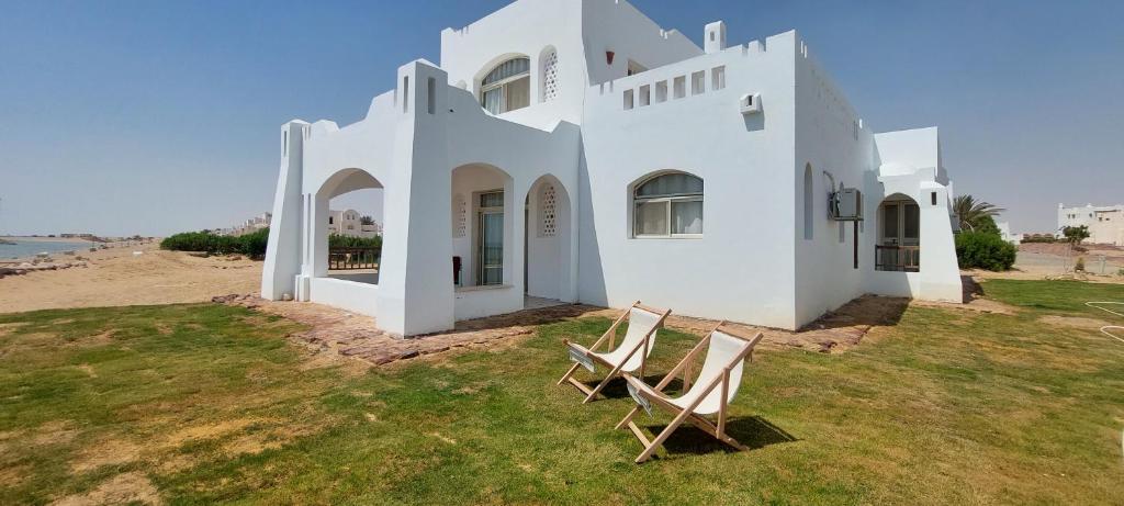 two chairs sitting in front of a white house at The white villas (TWV) in Ras Sedr