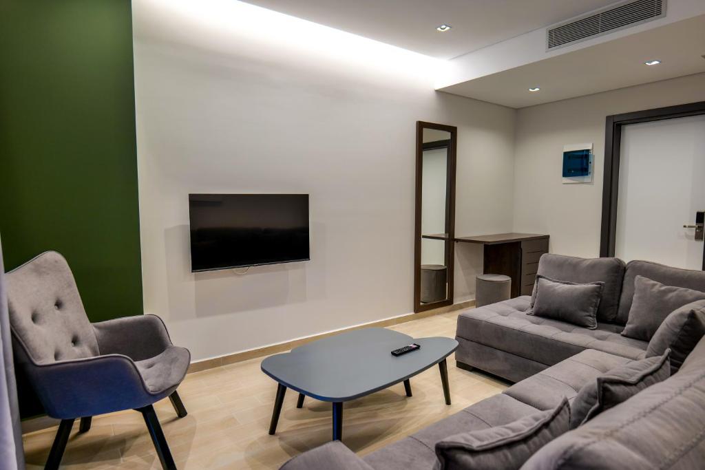 uma sala de estar com um sofá e cadeiras e uma televisão em NERIUM Hotel em Ksamil