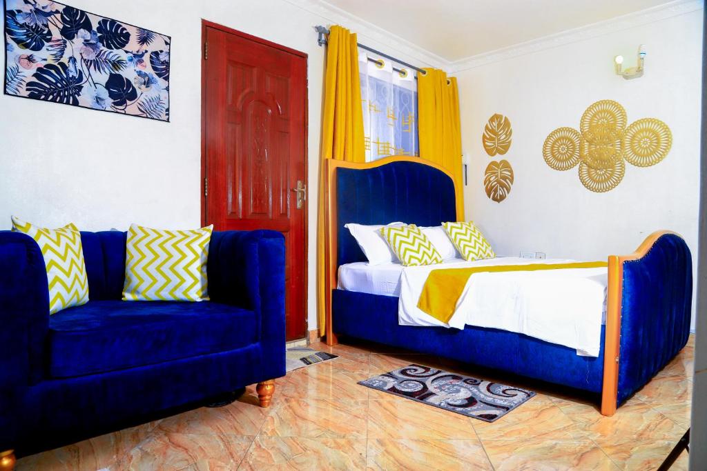 a bedroom with a bed and two blue chairs at Royal Haven A1 Apartment in Mombasa - Bamburi, 50" HDTV, WiFi, 6 mins to Beach in Mombasa