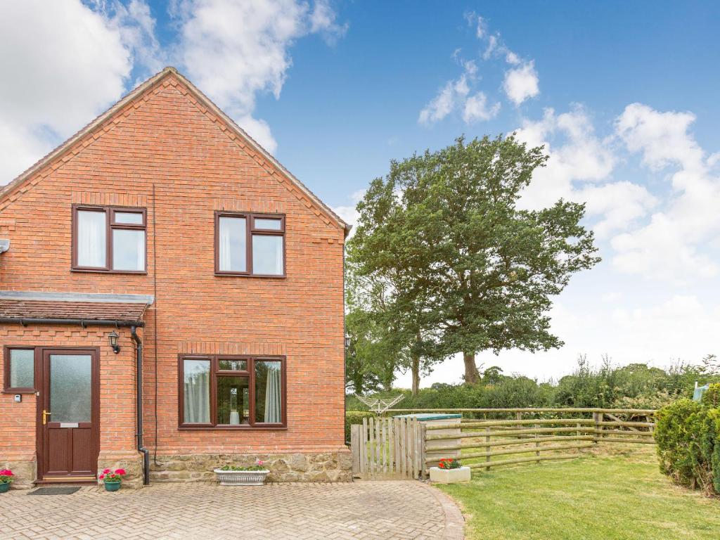 a brick house with a fence and a tree at The Willows in Church Stretton