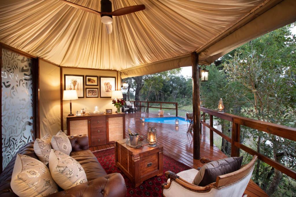 Hamiltons Tented Camp في Mluwati Concession : غرفة معيشة مع أريكة وسطح خشبي