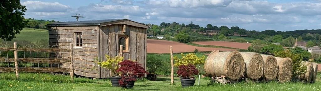 un pequeño edificio con fardos de heno en un campo en The Queen Bee Cabin en Hereford