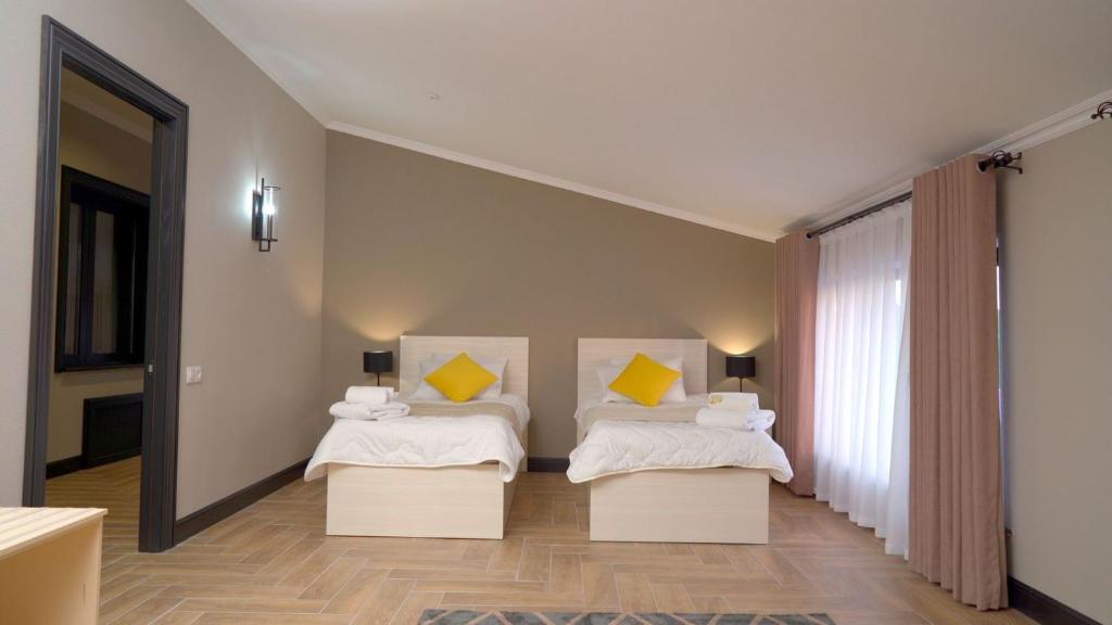 - une chambre avec 2 lits et des oreillers jaunes dans l'établissement Эдем, à Chimkent
