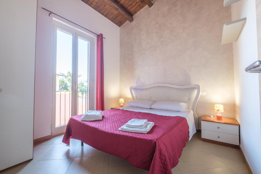 a bedroom with a bed with a pink blanket and a window at Casa Vacanza Josephine in Barcellona-Pozzo di Gotto