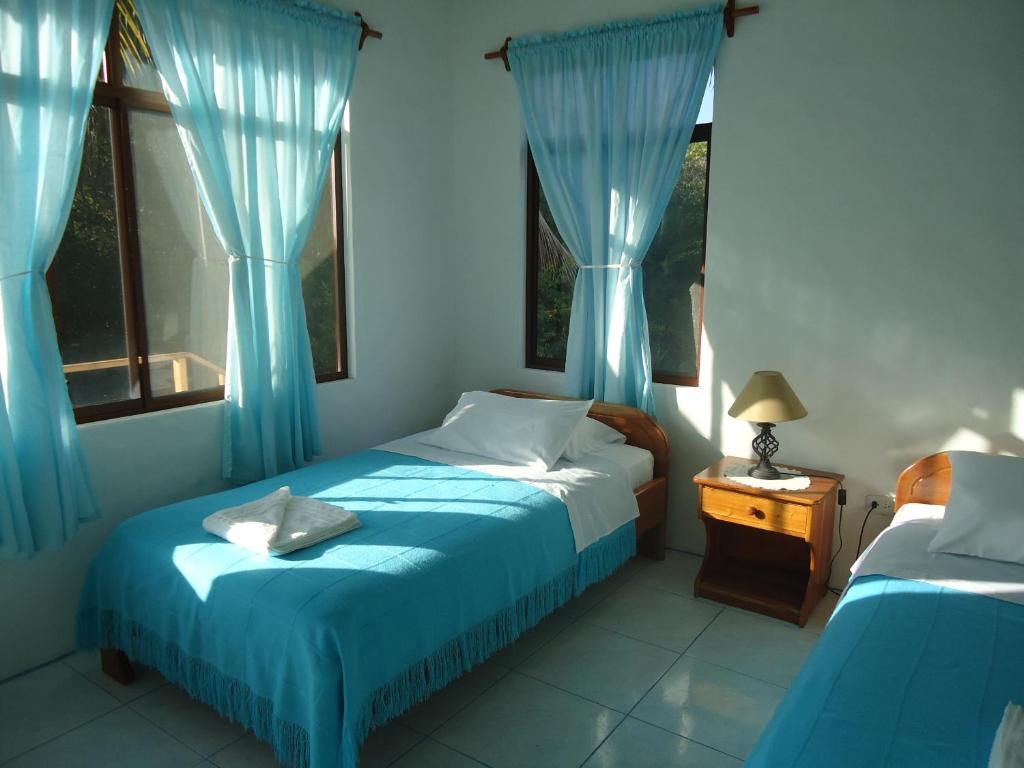 a bedroom with two beds and blue curtains at Cartago Bay in Puerto Villamil