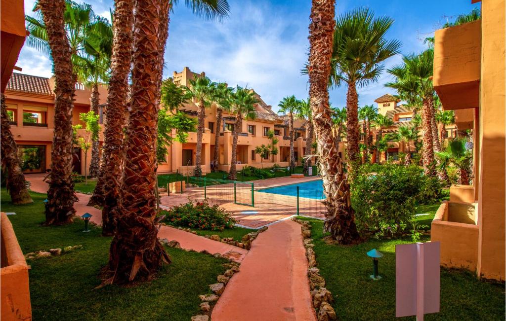 um pátio de resort com palmeiras e uma piscina em Lovely Apartment In Los Alczares With Kitchen em Los Alcázares