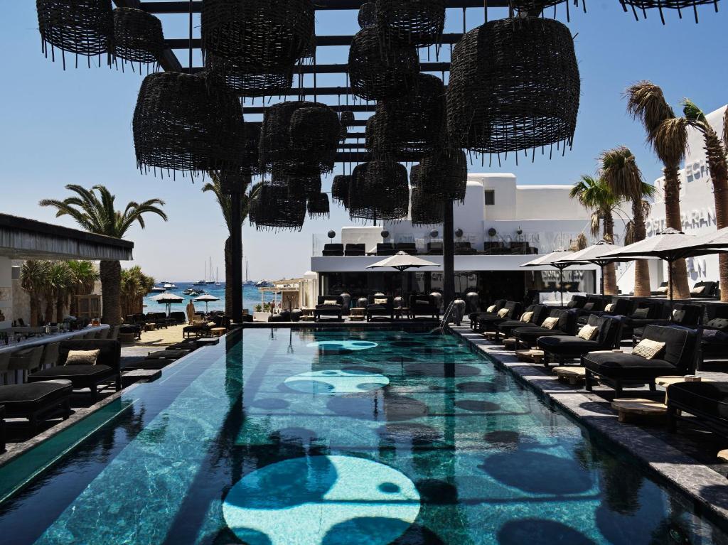 una piscina con sillas y un complejo en Myconian O, a Member of Design Hotels en Ornos