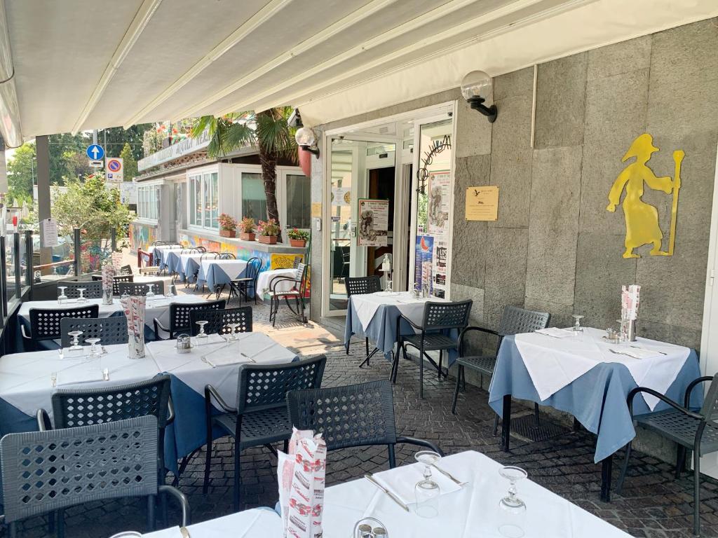 un restaurant avec des tables et des chaises blanches en face d'un bâtiment dans l'établissement Aquila Nera Di Tony, à Ivrea