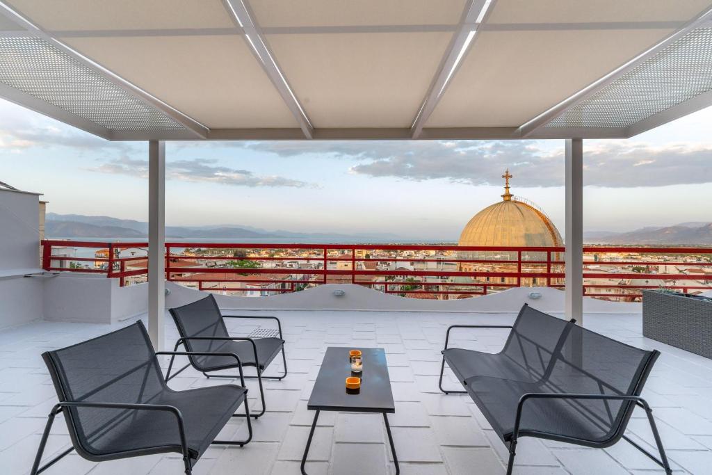 a patio with chairs and a table on a roof at John's city center roof studio flat -panorama view in Aigio